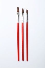 Photo of Different paint brushes on white background, top view