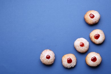 Hanukkah donuts with jelly and powdered sugar on blue background, flat lay. Space for text