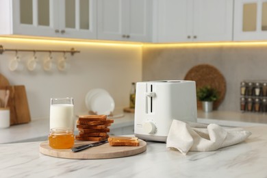 Breakfast served in kitchen. Toaster, crunchy bread, honey and milk on white marble table