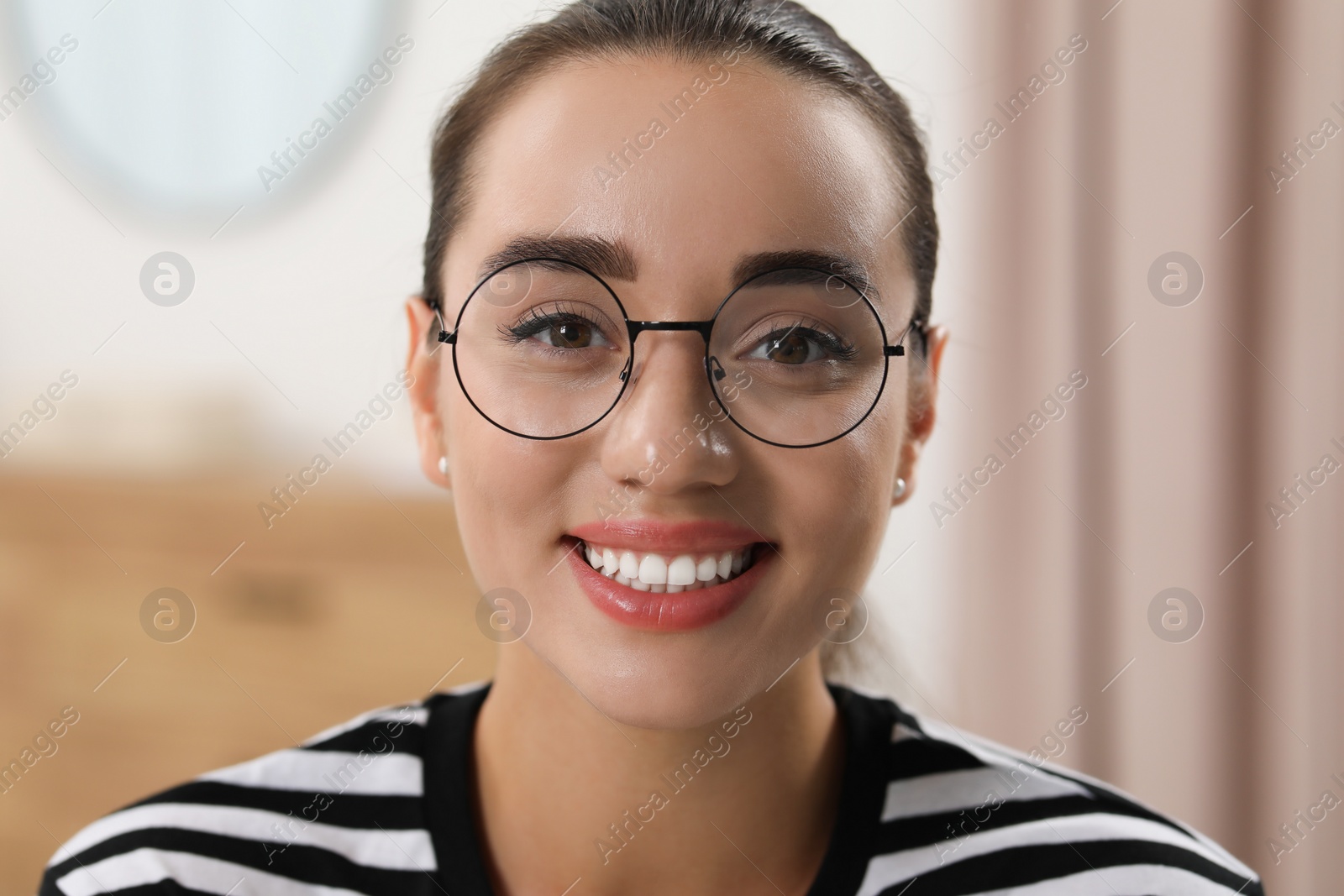 Photo of Portrait of beautiful young woman with glasses indoors. Attractive lady smiling and looking into camera