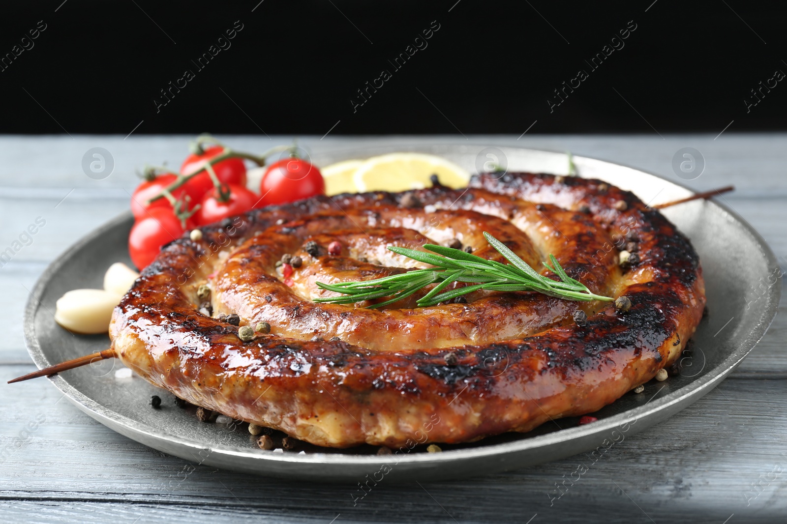 Photo of Delicious homemade sausage with spices, tomatoes and lemon on light grey wooden table, closeup