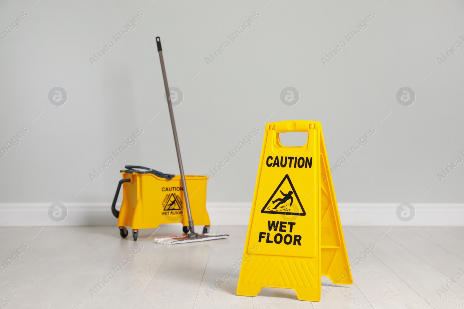 Photo of Safety sign with phrase Caution wet floor, mop and bucket indoors. Cleaning service
