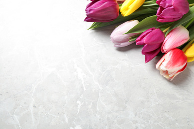 Photo of Beautiful spring tulips on marble table, closeup. Space for text