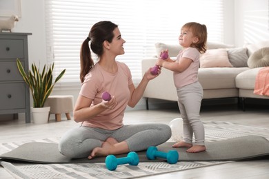 Photo of Mother and her daughter with dumbbells at home