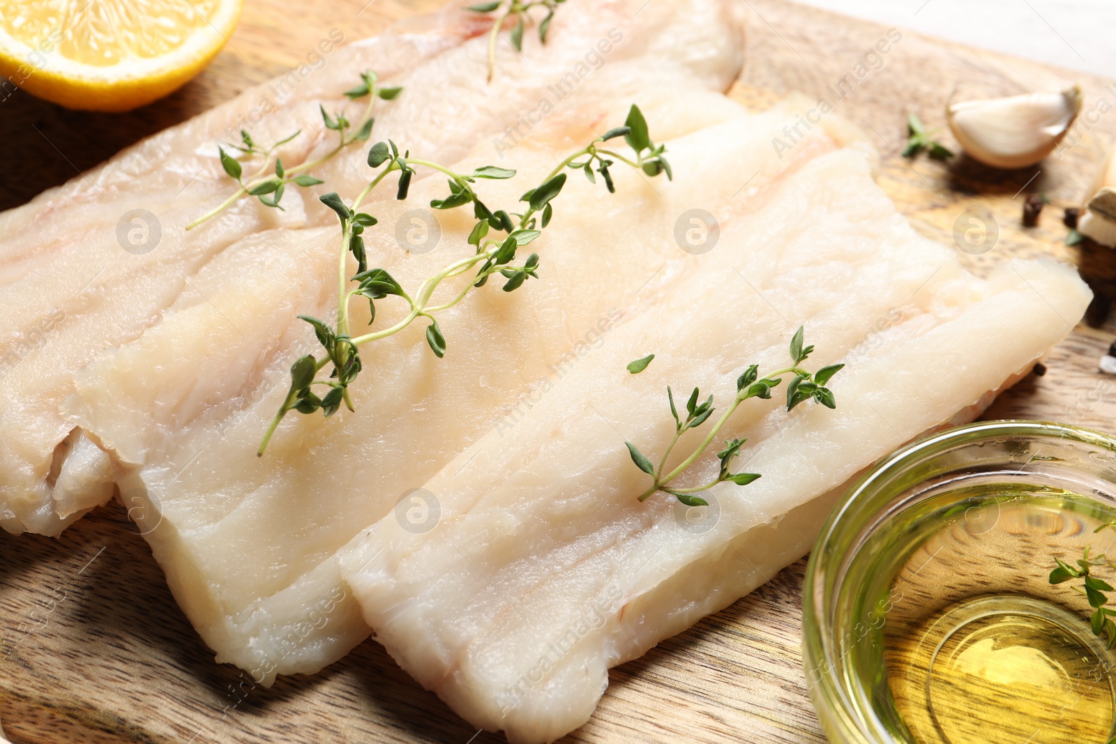 Photo of Raw cod fish, microgreens and oil on wooden table, closeup