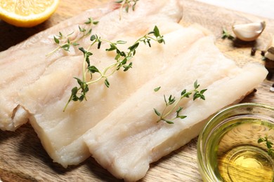 Photo of Raw cod fish, microgreens and oil on wooden table, closeup