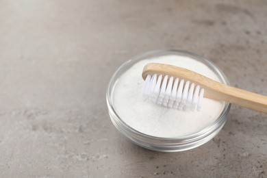 Photo of Bamboo toothbrush and bowl of baking soda on grey table. Space for text