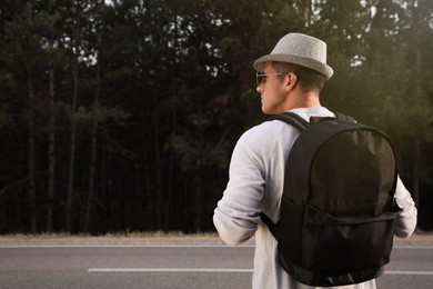 Man with backpack on road near forest