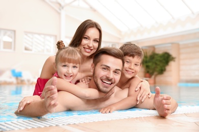 Happy family resting in indoor swimming pool