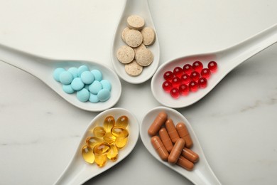 Photo of Spoons with different dietary supplements on white table, flat lay