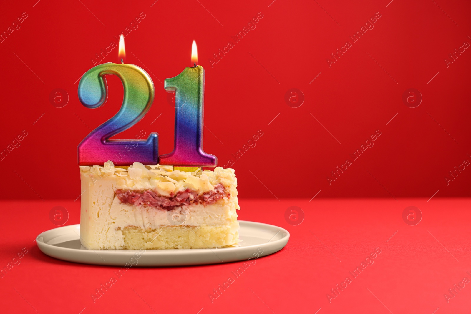 Photo of Coming of age party - 21st birthday. Delicious cake with number shaped candles on red background, space for text