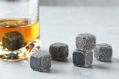 Photo of Whiskey stones and drink in glass on light table, closeup