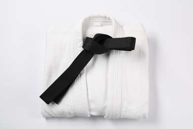 Photo of Black karate belt and kimono on white background, top view