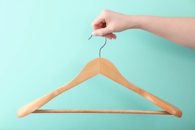 Photo of Woman holding hanger on turquoise background, closeup