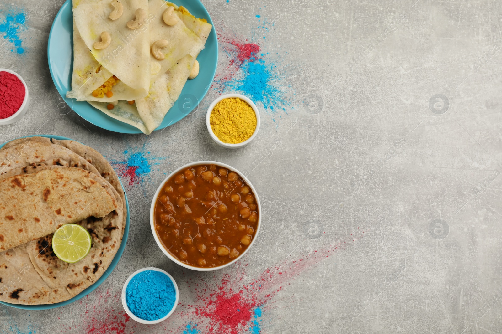 Photo of Traditional Indian food and color powders on grey table, flat lay with space for text. Holi festival celebration