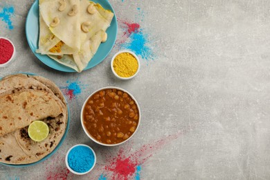 Traditional Indian food and color powders on grey table, flat lay with space for text. Holi festival celebration