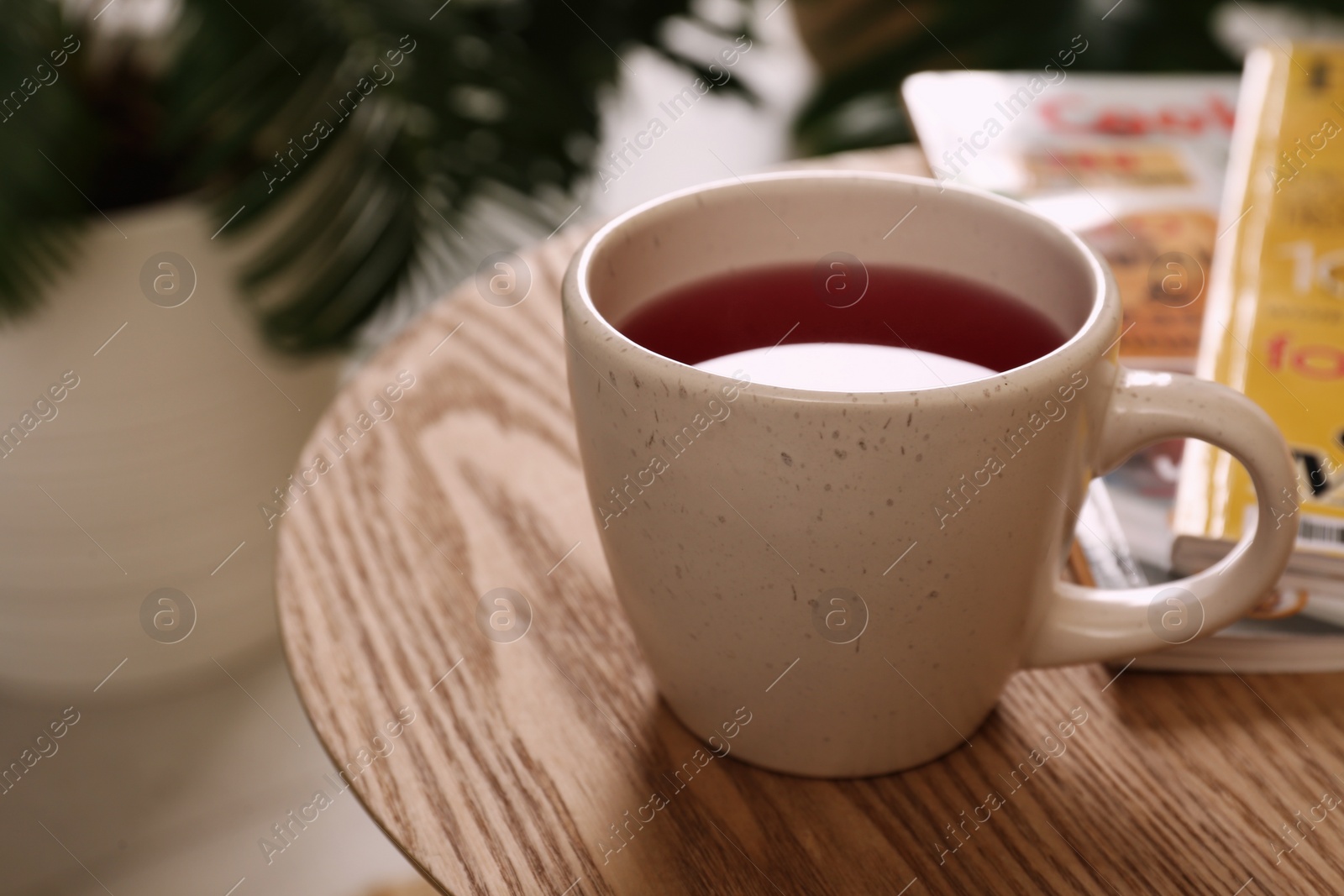 Photo of Cup of tea and magazines on wooden table indoors