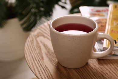 Cup of tea and magazines on wooden table indoors