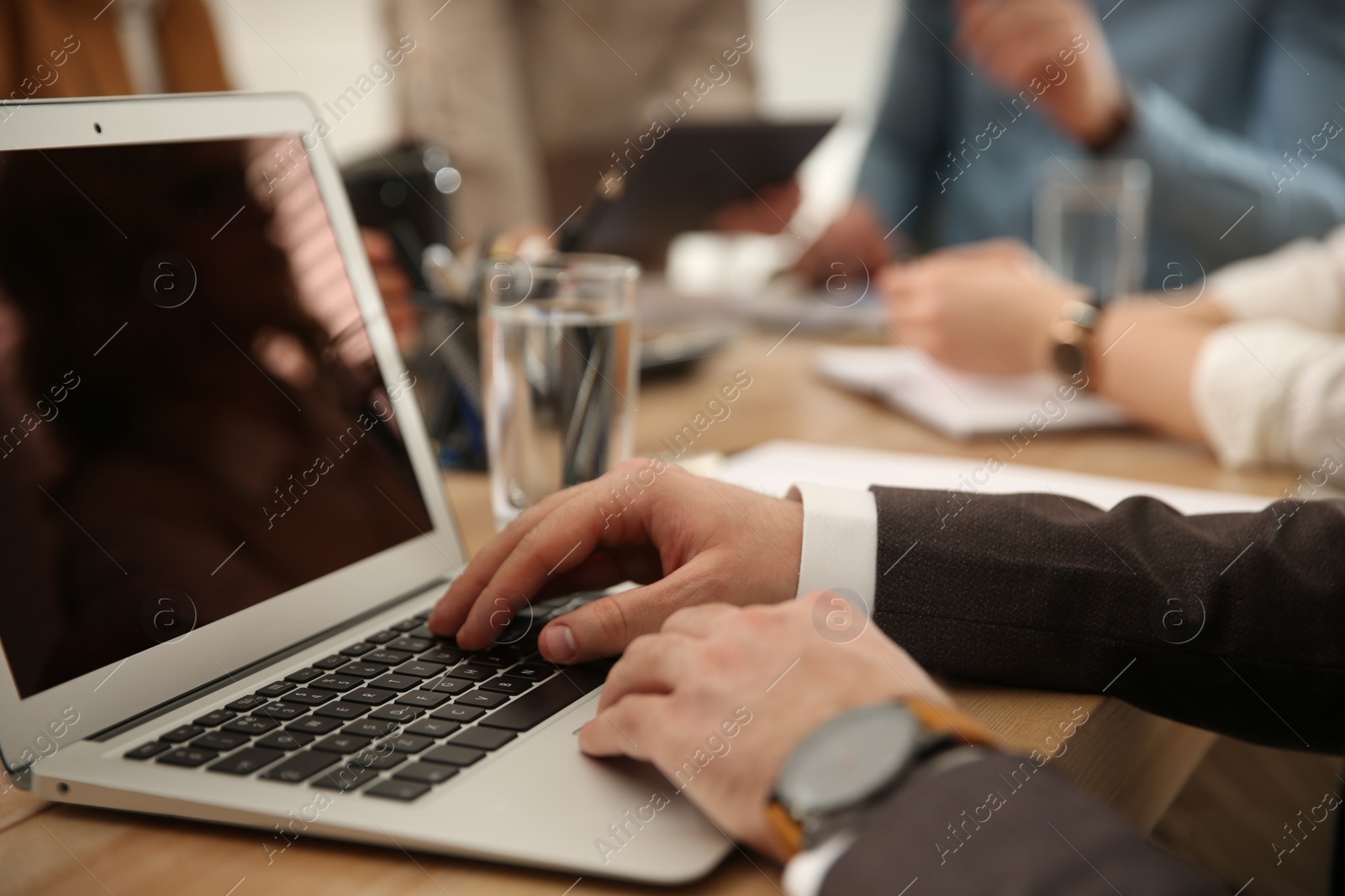 Photo of Man using laptop at table in office during business meeting, closeup. Management consulting