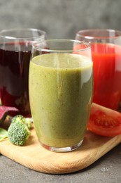 Delicious vegetable juices and fresh ingredients on grey table, closeup