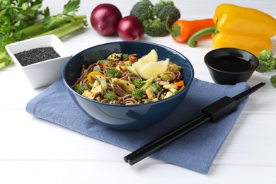 Photo of Stir-fry. Delicious cooked noodles with chicken and vegetables in bowl served on white wooden table