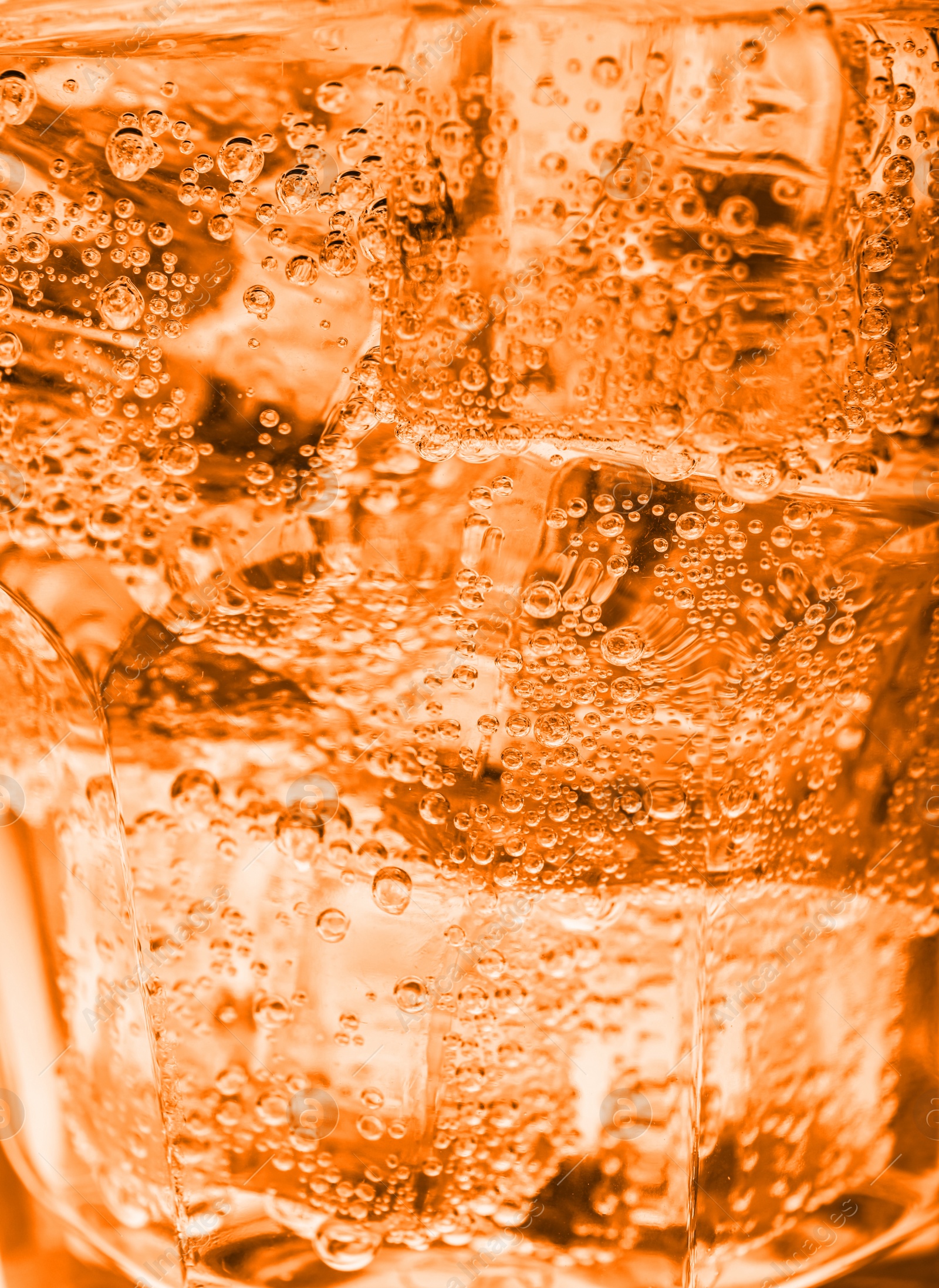 Image of Closeup view of soda water with ice in glass. Toned in glass