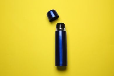 Photo of Blue metal thermos on yellow background, top view