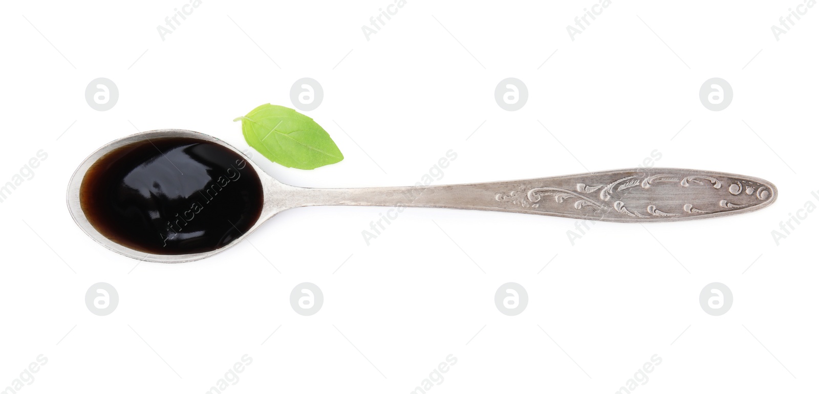 Photo of Metal spoon with balsamic glaze and basil leaf on white background, top view