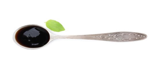 Photo of Metal spoon with balsamic glaze and basil leaf on white background, top view