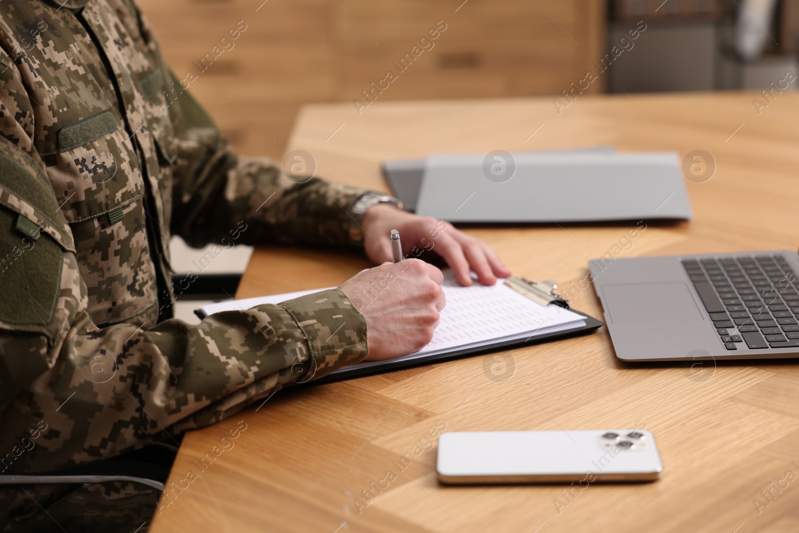 Photo of Military service. Soldier working at wooden table, closeup