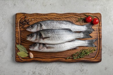 Tasty sea bass fish with spices on grey textured table, top view