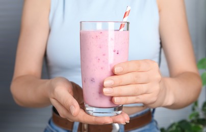 Photo of Woman holding glass of tasty raspberry smoothie indoors, closeup