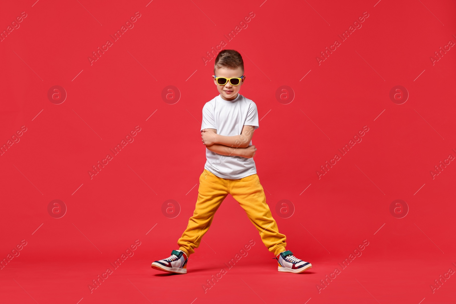 Photo of Happy little boy dancing on red background