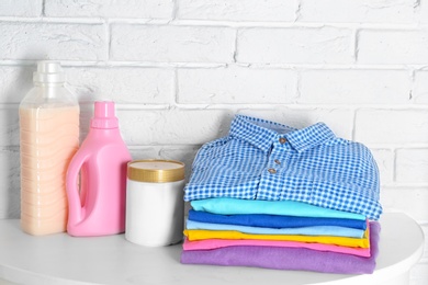 Stack of clean clothes and bottles with detergent on table