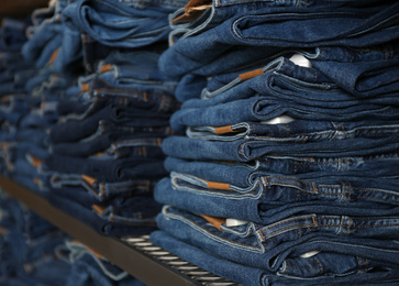 Photo of Collection of stylish jeans on shelf in shop