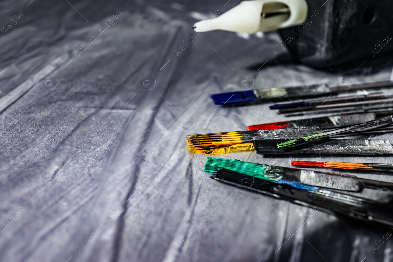 Photo of Tattoo needles covered with colorful inks on table, closeup. Space for text