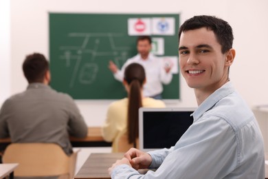 Happy man at desk in class during lesson in driving school