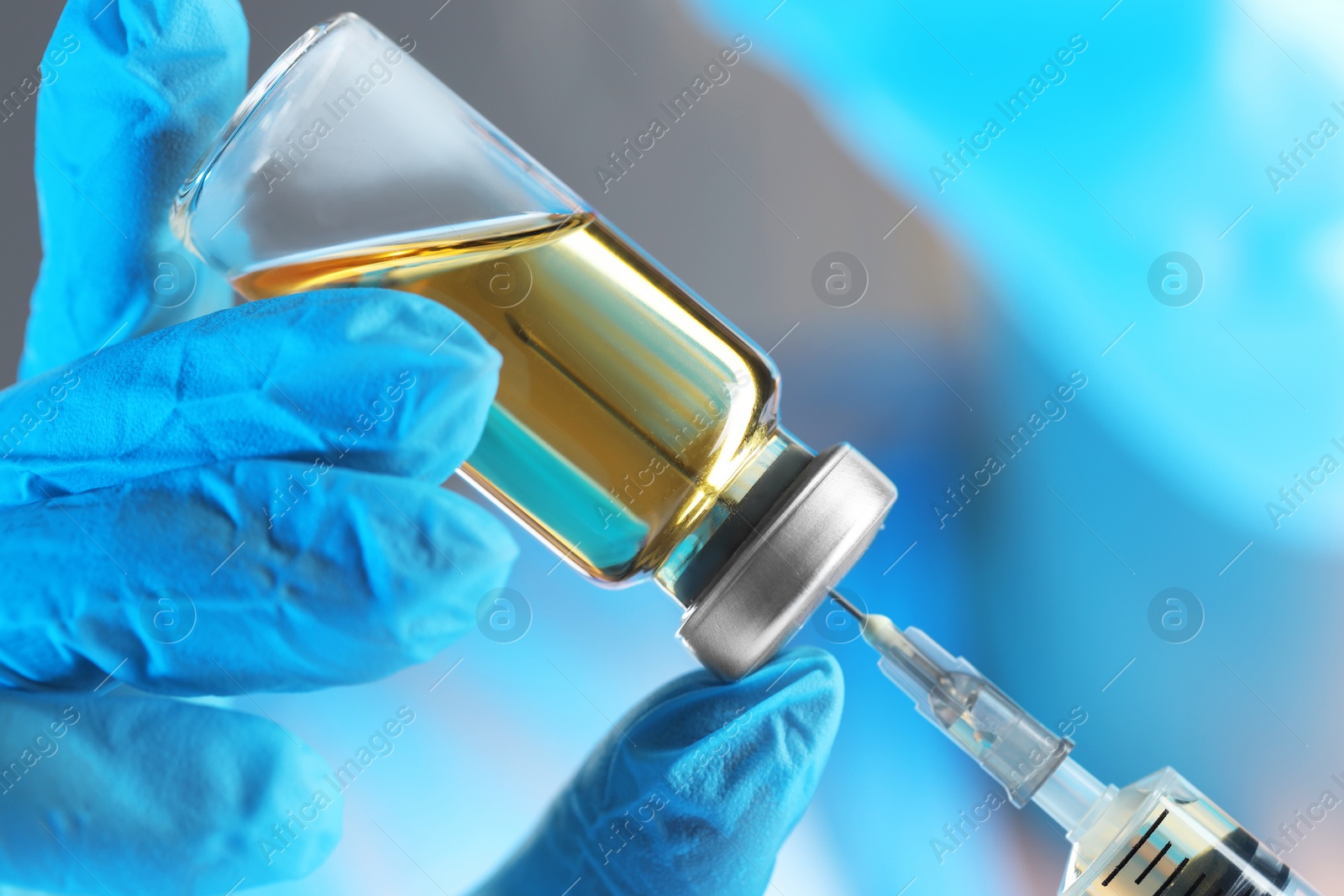 Photo of Doctor filling syringe with medication from glass vial, closeup