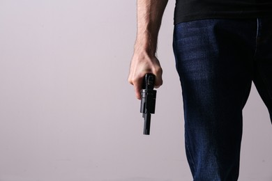Photo of Man holding gun on grey background, closeup. Space for text