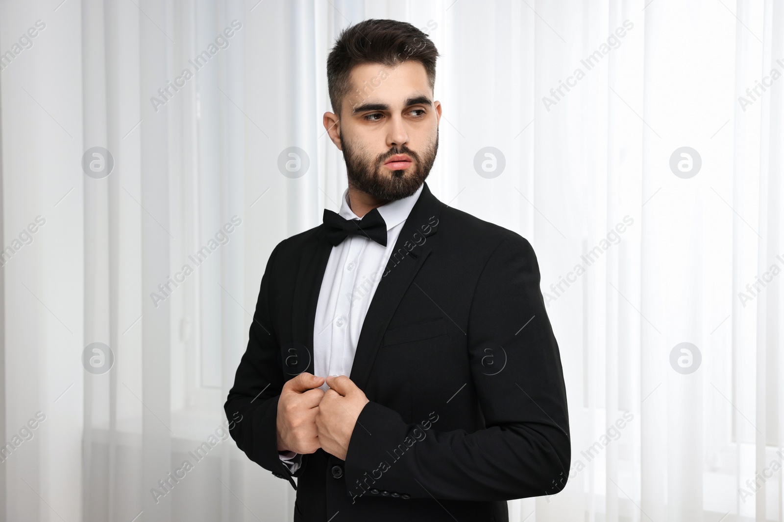 Photo of Portrait of handsome man in suit, shirt and bow tie indoors