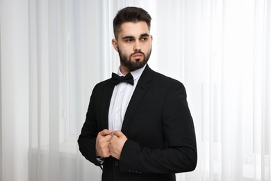 Portrait of handsome man in suit, shirt and bow tie indoors