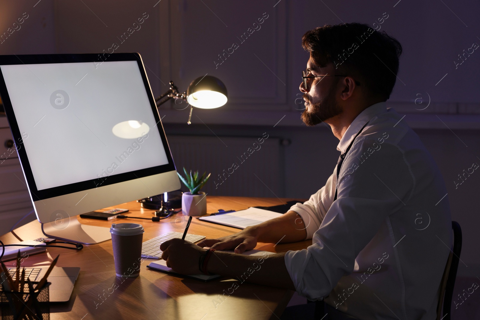 Photo of Tired young man working late in office