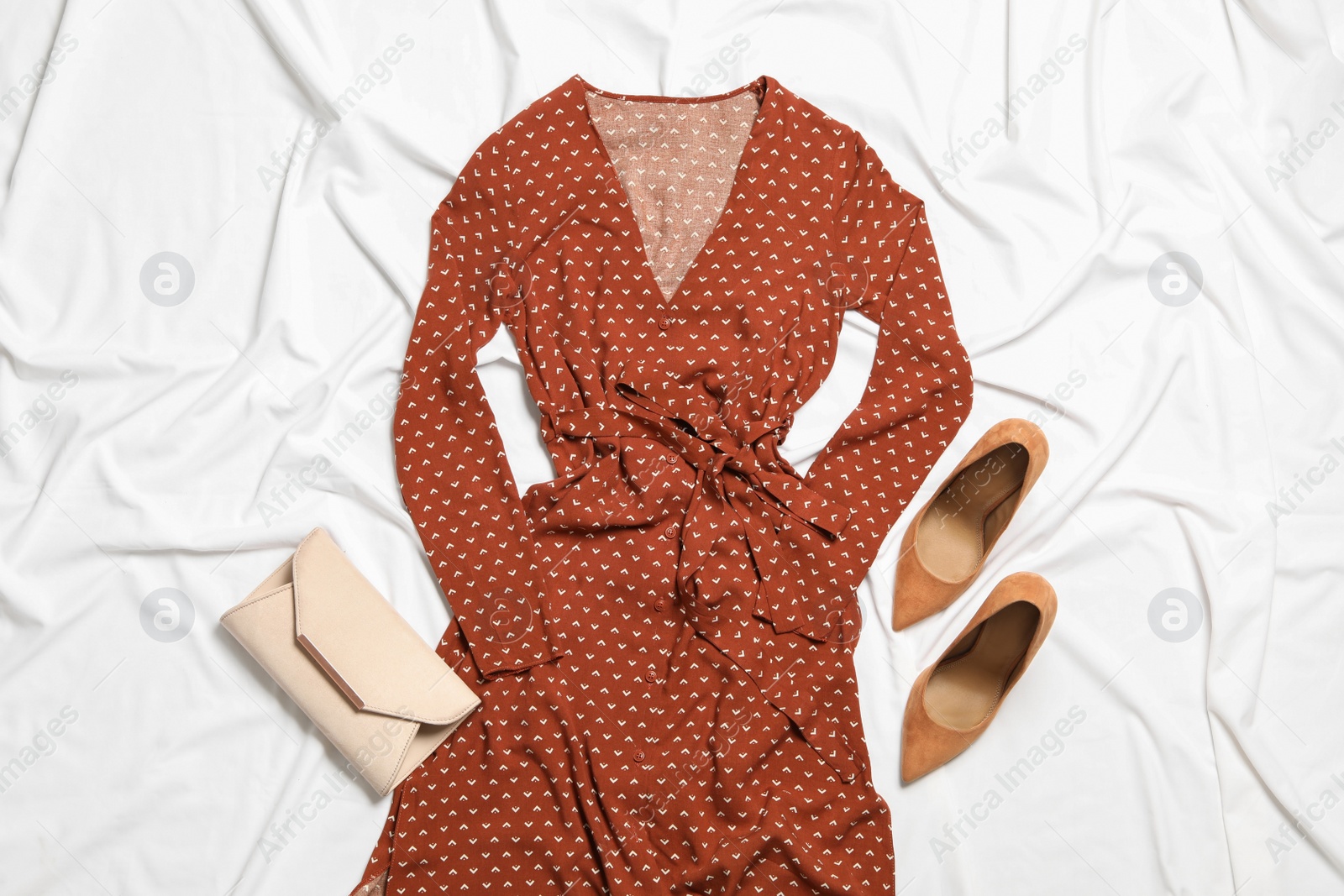 Photo of Stylish red dress, bag and shoes on white fabric, flat lay