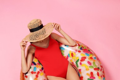 Photo of Young woman in stylish swimsuit on inflatable ring against pink background, top view