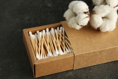 Photo of Cotton swabs and flowers on black table, closeup