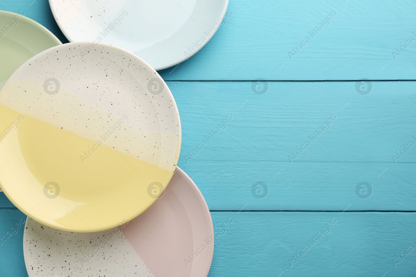 Photo of Beautiful ceramic plates on light blue wooden table, flat lay. Space for text