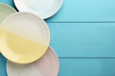 Beautiful ceramic plates on light blue wooden table, flat lay. Space for text