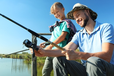 Photo of Father and son fishing together on sunny day