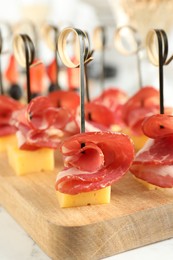 Tasty canapes with cheese and ham on white marble table, closeup