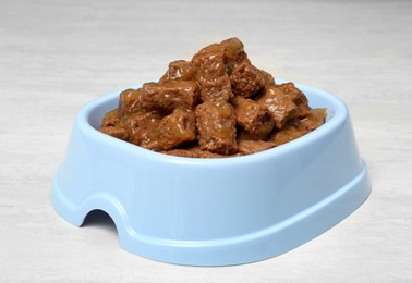 Photo of Wet pet food in feeding bowl on white table